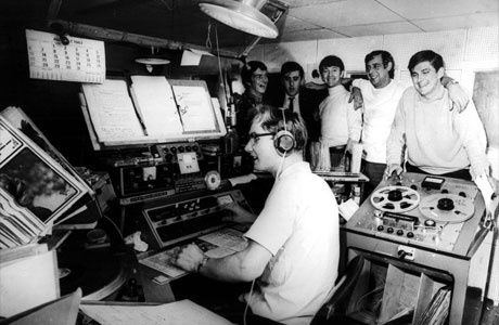 Svartvit bild av radiotekniker och personal i en trång radiostudio